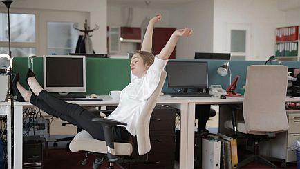 Frau auf Stuhl im Büro macht Fitnessübungen