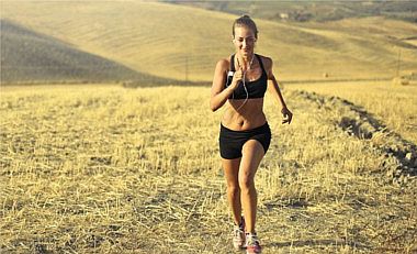Frau  joggt auf Feld um sich fit zu halten