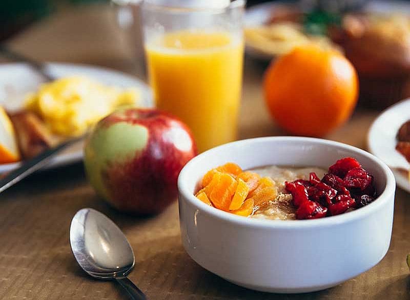 Ein Glas Orangensaft, ein Musli und Früchte auf einem Tisch damit kann man clever Abnehmen. Eine gesunde Ernährung