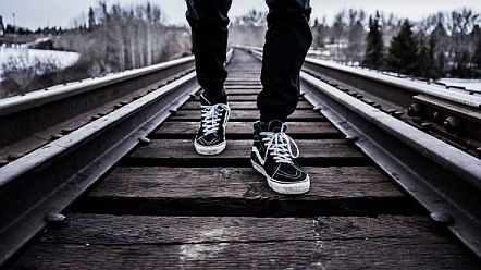 Mann geht auf Schienen spazieren